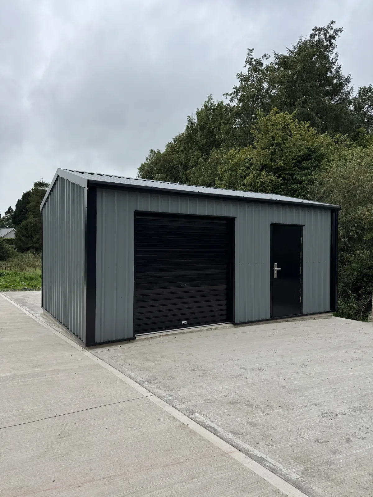 Grey steel garage with a black roller door and personnel door